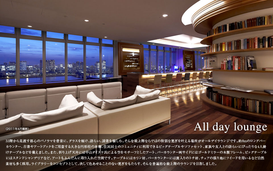 All day lounge 33階から見渡す都心のパノラマを背景に、グラスを傾け、語らい、読書を愉しむ。そんな最上階ならではの特別な寛ぎを叶える場所がオールデイラウンジです。約8mのロングバーカウンター、古書やアートブックをご用意する大きな円形柱の本棚、住民同士のコミュニティに利用できるビッグテーブルやソファセット、家族や友人との計らいにぴったりな4人掛けテーブルなどを揃えました。また、織り上げ天井には中山ダイスケ氏による空をモチーフとしたアート、バーカウンター両サイドにはゴールドミラーの木製フレーム、ビッグテーブルにはスタンドシャンデリアなど、アートもふんだんに取り入れた空間です。テーブルにはカリン材、バーカウンターには班入りのトチ材、チェアの張り地にツイードを用いるなど自然素材も多く採用。ライブラリーをコンセプトとして、決して色褪せることのない寛ぎをもたらす、そんな普遍的な最上階のラウンジを目指しました。