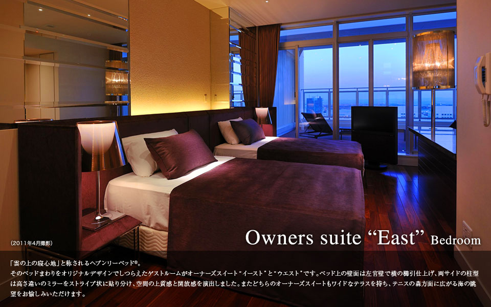 Owners suite East Bedroom 「雲の上の寝心地」と称されるヘブンリーベッド。そのベッドまわりをオリジナルデザインでしつらえたゲストルームがオーナーズスイートイーストとウェストです。ベッド上の壁面は左官壁で横の棚引仕上げ、両サイドの柱型は高さ違いのミラーをストライプ状に貼り分け、空間の上質感と開放感を演出しました。また、どちらのオーナーズスイートもワイドなテラスを持ち、テニスの森方向に広がる海の眺望をお愉しみいただけます